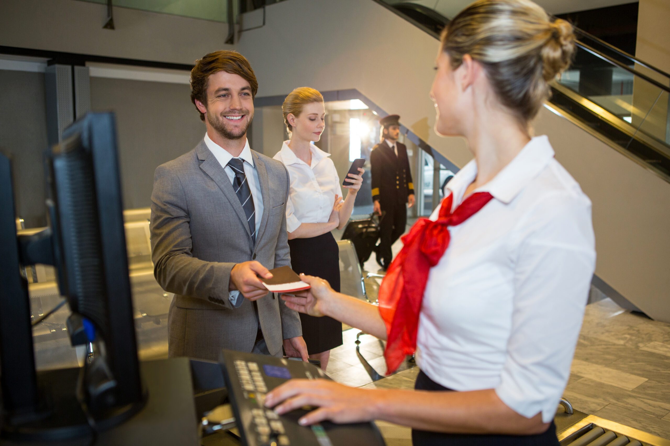 Businessman giving his boarding pass to the female staff at the check in desk in the airport terminal